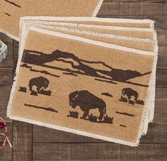 three placemats with elephants on them sitting on a wooden table next to yarn and scissors