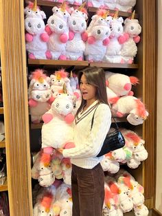 a woman is standing in front of a shelf full of stuffed animals and unicorns