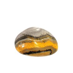 a yellow and black rock sitting on top of a white surface in front of a white background