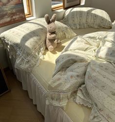 a stuffed animal sitting on top of a bed next to pillows and blankets in a room