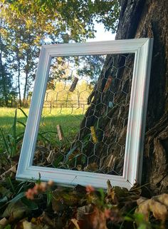 a white frame sitting on the ground next to a tree