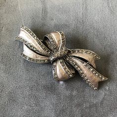 This beautiful bow brooch is silver in color and has a filigree design.  It is trimmed with tiny pave rhinestones.  It is really stunning and would look great on a dressy black outfit! It measures 3" by 1 1/4" and has a C clasp for easy closure. This item ships free in the Continental United States.  Thank you for stopping by my Etsy shop! Elegant Anniversary Brooch With Bow, Elegant Rhinestone Brooch For Party, Elegant Brooches With Decorative Bow For Anniversary, Elegant Silver Brooches For Vintage Events, Silver Bow Brooch For Wedding, Silver Brooches With Decorative Bow, Elegant Anniversary Brooches With Decorative Bow, Silver Brooch With Decorative Bow, Silver Brooch With Decorative Bow For Party