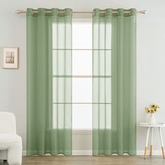 a living room with green curtains and a white chair