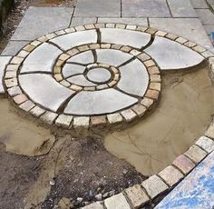 a circular stone design is in the middle of a garden area that has been built into concrete