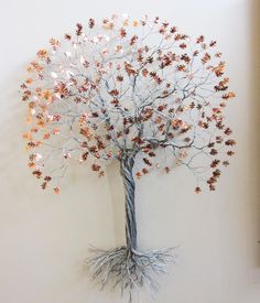 a metal tree with lots of leaves on it's branches is mounted to the wall