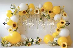 the balloon arch is decorated with sunflowers, daisies and baby's breath