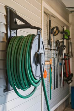 a hose is hanging on the wall next to a garden hose holder