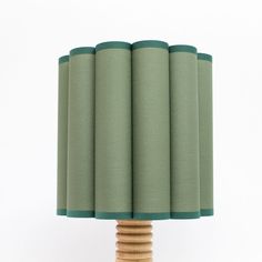 a wooden table lamp with four green lampshades on top of the base,