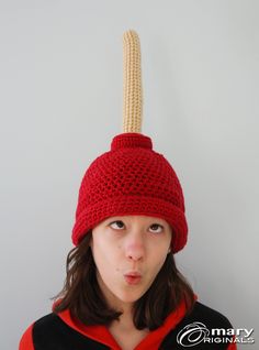 a woman wearing a red knitted hat with a rope attached to it's head