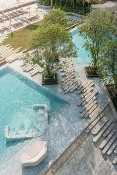 an aerial view of a swimming pool with lounge chairs and trees in the foreground