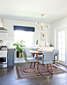 a dining room table with four chairs and a rug on the floor in front of it