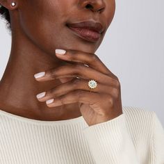 a woman wearing a white sweater and diamond ring