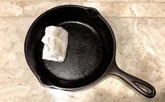 a cast iron skillet with a piece of paper in it on a marble counter top