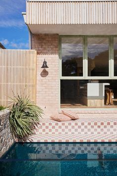 a house with a pool in front of it and an outdoor shower area next to the swimming pool