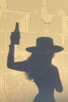 a shadow of a person with a hat holding a bottle