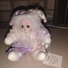 a stuffed animal with white hair and blue eyes sitting next to a tag on the floor