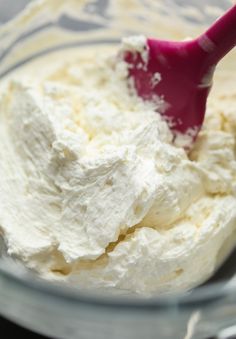 whipped cream in a glass bowl with a red spoon