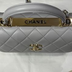 Avec sa silhouette structurée et ses lignes épurées, ce sac se distingue par son allure chic et polyvalente. Le sac Chanel modèle Trendy est une pièce emblématique qui allie sophistication intemporelle et modernité. Dans une teinte gris éléphant, ce sac incarne l'élégance discrète caractéristique de la marque Chanel. • État : A - Neuf • Dimensions : 25 x 17 x 11 cm • Matière : Cuir d’agneau • Couleur : Gris éléphant • Vendu avec : Fullset Luxury Box Bag With Detachable Handle For Shopping, Luxury Shopping Box Bag With Detachable Handle, Designer Everyday Luxury Top Handle Bags, Designer Top Handle Bag For Everyday Luxury, Designer Tote Flap Bag With Gold-tone Hardware, Designer Flap Bag With Gold-tone Hardware Tote, Designer Flap Bag With Gold-tone Hardware For Shopping, Luxury Rectangular Bags With Detachable Handle, Luxury Rectangular Bag With Detachable Handle