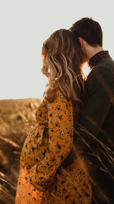 a man and woman are kissing in the field