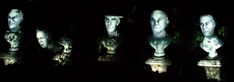 several busturines are lit up in the dark with their faces projected on them