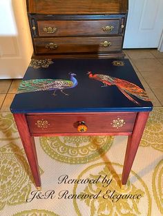 a table with two peacocks painted on it next to an old chest of drawers