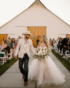 a bride and groom are walking down the aisle at their wedding in front of a barn