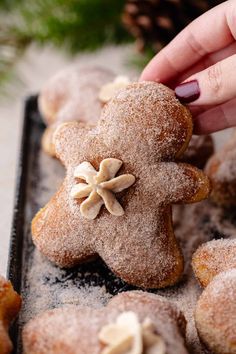 a hand is picking up some sugared cookies from a tray with other pastries