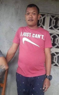 a man standing in front of a wall wearing a pink t - shirt that says i just can't