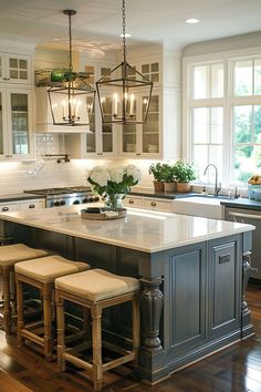 a large kitchen island with stools in front of it and lights hanging from the ceiling