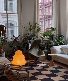 a living room filled with furniture and lots of plants on the windows sills