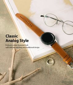 a book with glasses and a watch on it next to a pair of eyeglasses