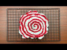 a red and white striped flower sitting on top of a metal wire cooling grate