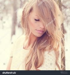 a beautiful blonde woman with long hair in the snow looking down at her face and head