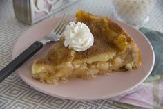 a piece of pie with whipped cream on top sits on a pink plate next to a fork