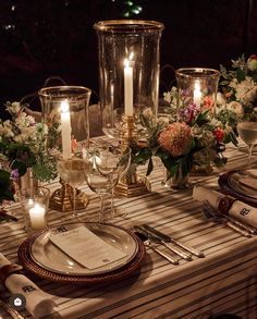 the table is set with candles, plates and silverware for an elegant dinner party