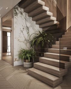 there is a potted plant next to the stairs in this modern style house with marble walls and wood flooring