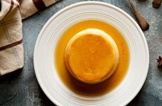 a white plate topped with an orange sauce on top of a blue table cloth next to utensils