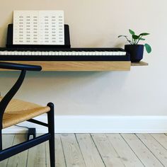 a wooden chair sitting next to a desk with a keyboard on it and a potted plant