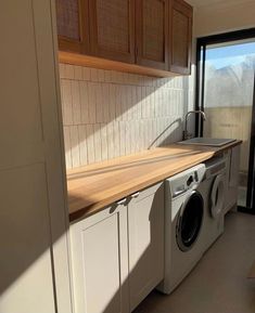 a washer and dryer in a small room with wooden counter tops on the side