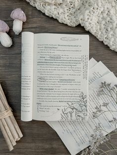 an open book sitting on top of a wooden table next to some garlic and mushrooms