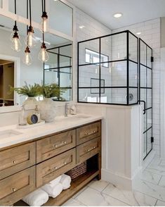 a bathroom with two sinks, mirrors and lights on the wall above it is also a walk in shower