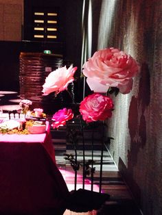 some pink flowers are in a vase on a table with candles and other items around it