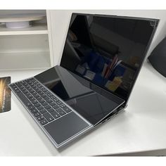 an open laptop computer sitting on top of a white desk next to a mouse pad