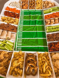 an assortment of snacks are arranged in trays on a table with green and white stripes