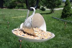 a bird feeder filled with lots of birdseed in the middle of a green yard