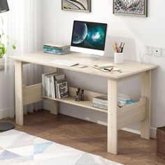 a desk with a computer on top of it in front of a window and bookshelf