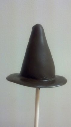 a chocolate hat sitting on top of a wooden stick in front of a white wall