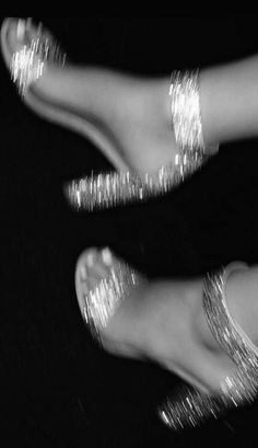 two pairs of feet with shiny silver glitters on them and one pair is in the air