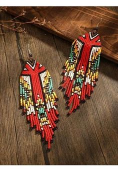 two pairs of red, yellow and green beaded earrings on top of a wooden table