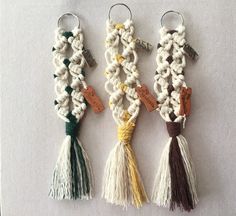 three key chains with tassels and tags attached to them on a white surface